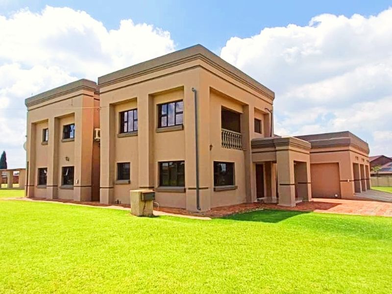 A spacious multi-story farm residence featuring a large lawn, paved driveway, integrated multi-car garage, and an upper-level balcony.