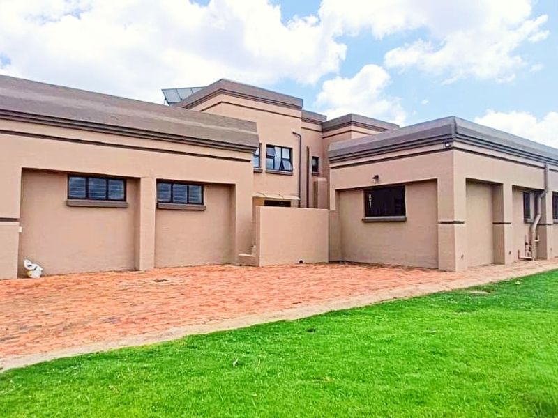 Rear view of a modern farm-style residence featuring a brick paved patio area, expansive lawn, and integrated solar water heating system.