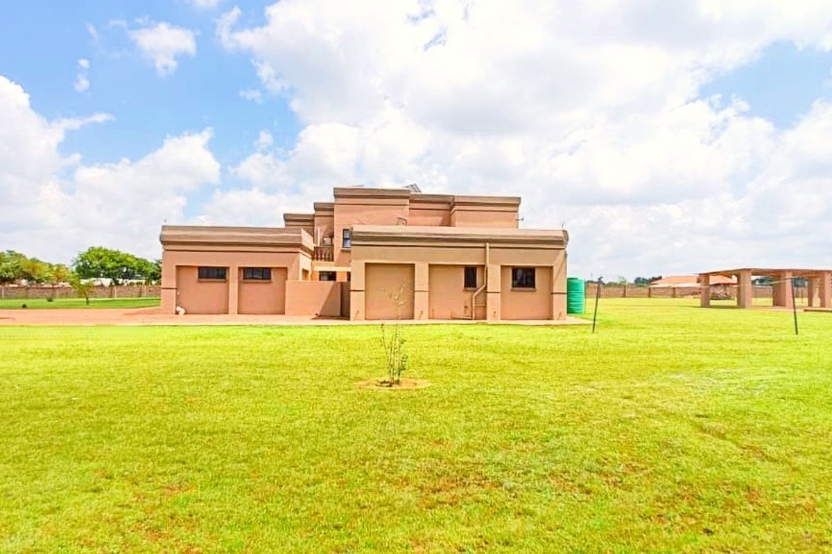 A wide-angle view of the rear elevation of the farm property, featuring a large, expansive lawn and perimeter fencing.