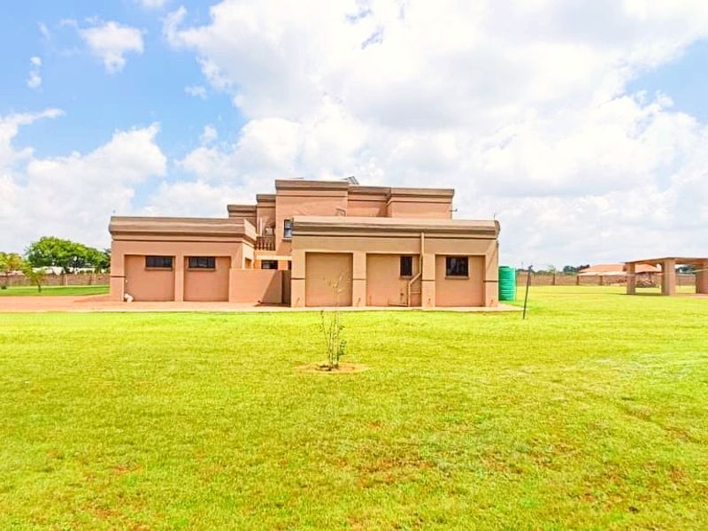 A wide-angle view of the rear elevation of the farm property, featuring a large, expansive lawn and perimeter fencing.