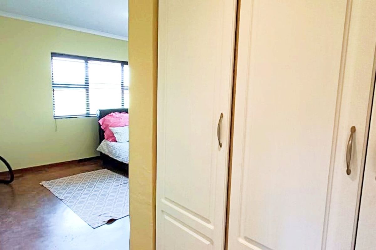 A bedroom featuring built-in cupboards and a window, providing a functional space with neutral wall finishes.
