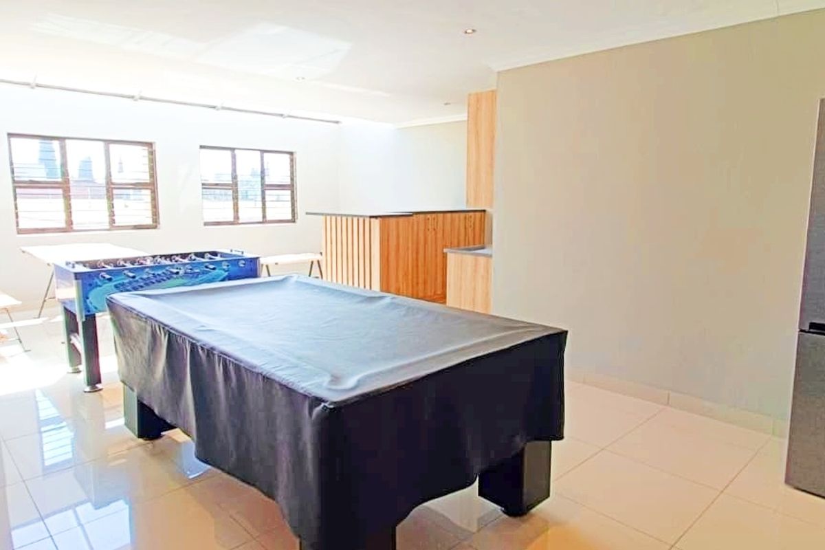 Spacious living area featuring tiled flooring, recessed lighting, and a built-in bar counter, suitable for entertainment or recreational use.