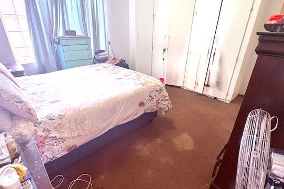 A bedroom featuring built-in wardrobes and carpeted flooring, offering a functional space with potential for cosmetic updates.
