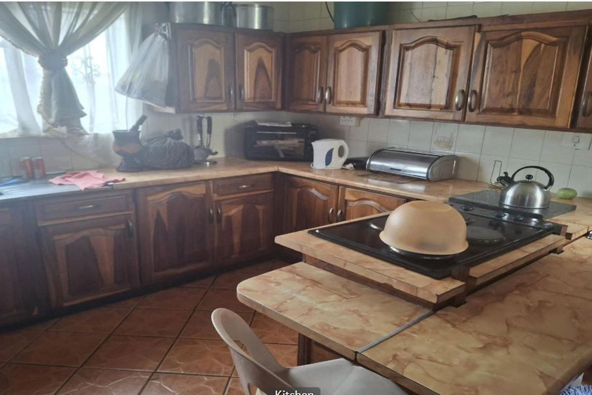A functional kitchen featuring traditional wooden cabinetry, laminate countertops, a built-in hob, and tiled flooring, offering a classic layout with ample storage space.