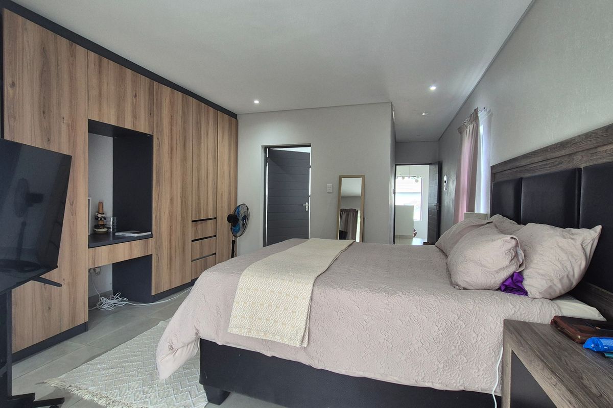 A well-maintained bedroom featuring extensive built-in wooden cabinetry, recessed ceiling lighting, and neutral tiled flooring.