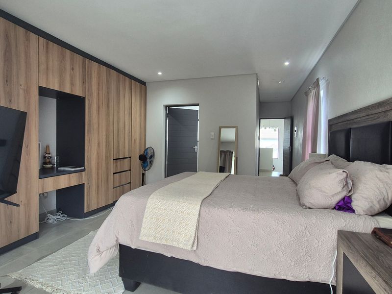 A well-maintained bedroom featuring extensive built-in wooden cabinetry, recessed ceiling lighting, and neutral tiled flooring.
