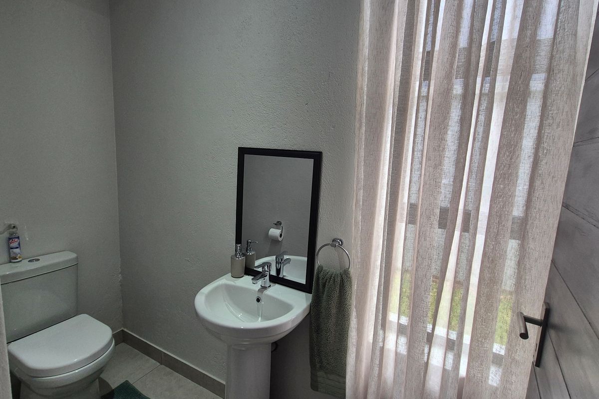 A functional guest bathroom featuring a pedestal basin, toilet, and tiled flooring, providing a clean and practical space.