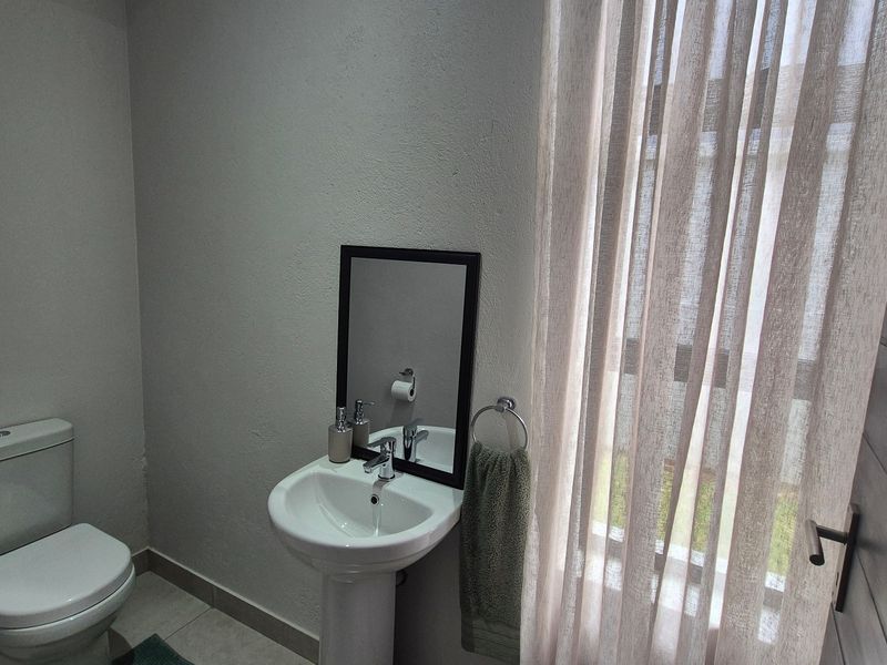 A functional guest bathroom featuring a pedestal basin, toilet, and tiled flooring, providing a clean and practical space.