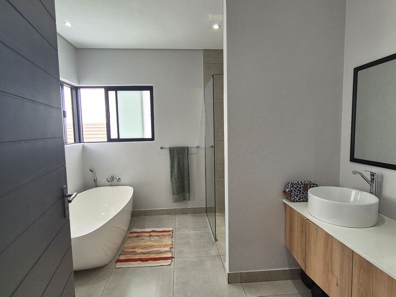Modern bathroom featuring a sleek freestanding bathtub, a walk-in shower with glass enclosure, and a contemporary vanity with a vessel sink.