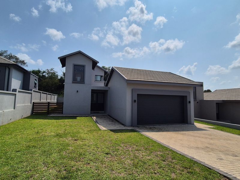 Modern residential property featuring a paved driveway, single garage, and well-maintained front lawn with perimeter boundary walls.