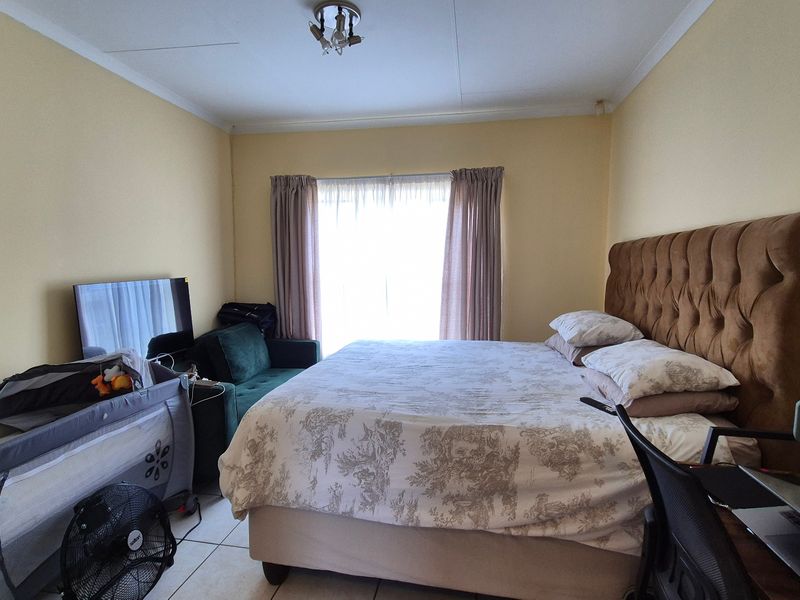 A functional bedroom featuring tiled flooring and neutral wall finishes, providing a comfortable space with natural light from the window.