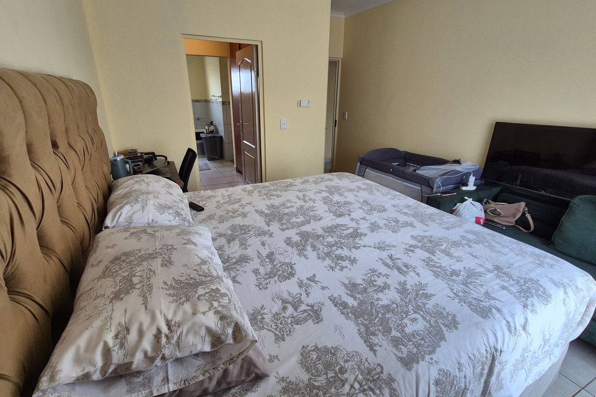 A spacious bedroom featuring tiled flooring and direct access to an adjoining bathroom, offering a functional layout with neutral wall finishes.