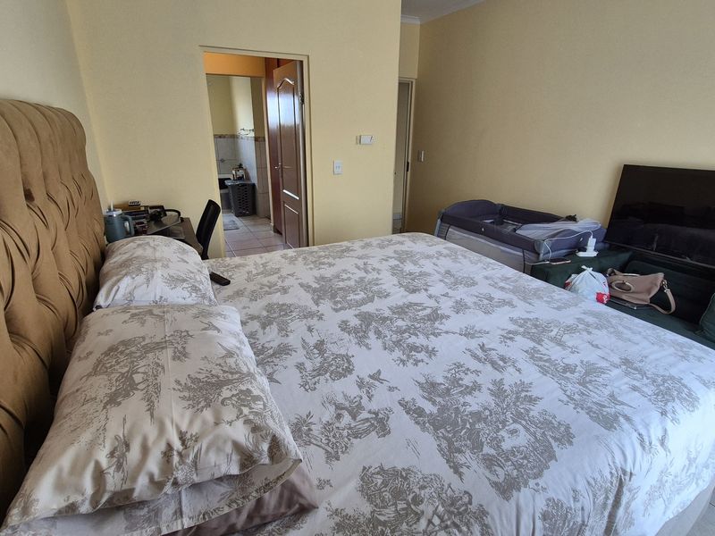 A spacious bedroom featuring tiled flooring and direct access to an adjoining bathroom, offering a functional layout with neutral wall finishes.