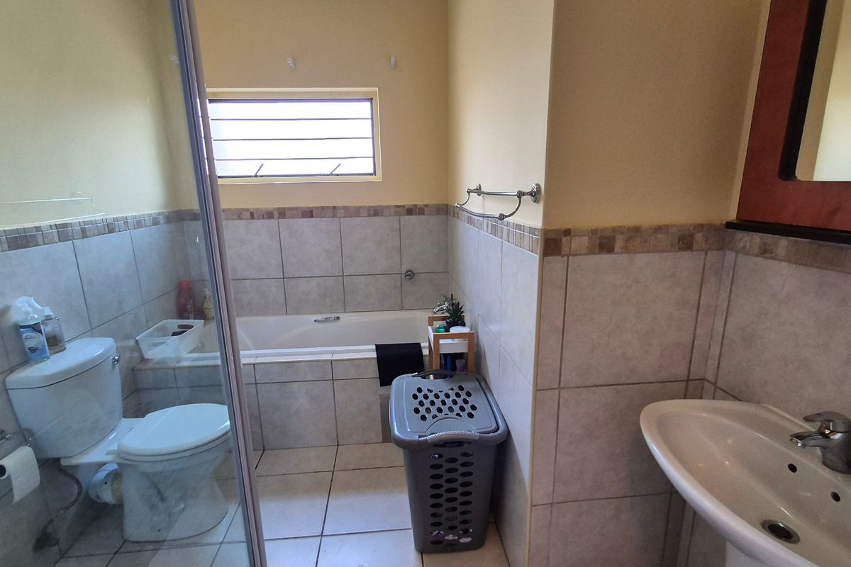 A functional bathroom featuring a shower enclosure, bathtub, pedestal basin, and tiled finishes throughout.