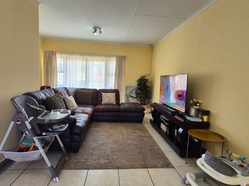 A comfortable living room featuring tiled flooring and a large sliding glass door that provides natural light to the space.