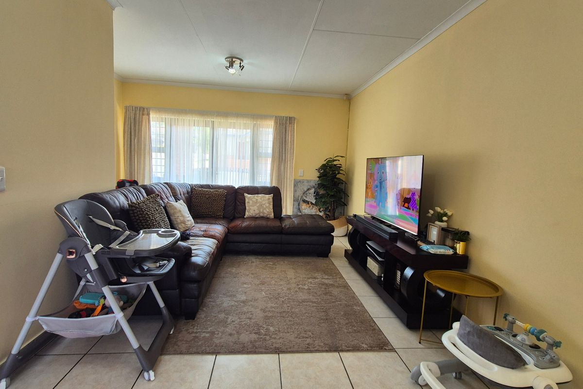 A comfortable living room featuring tiled flooring and a large sliding glass door that provides natural light to the space.