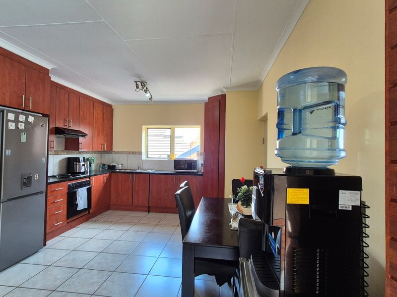 A functional kitchen featuring wood-finish cabinetry, dark countertops, tiled flooring, and integrated appliances, offering a practical layout for daily cooking and dining.
