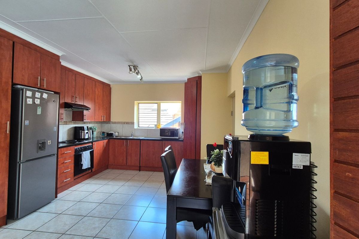 A functional kitchen featuring wood-finish cabinetry, dark countertops, tiled flooring, and integrated appliances, offering a practical layout for daily cooking and dining.