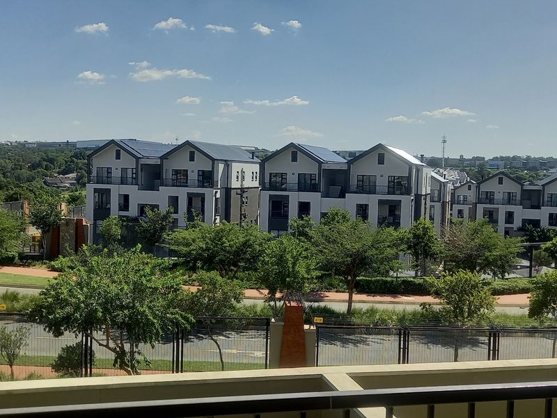 An elevated view overlooking a residential complex and surrounding greenery from a balcony.