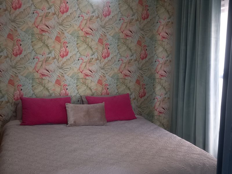 A bedroom featuring patterned wallpaper and a view through a doorway.