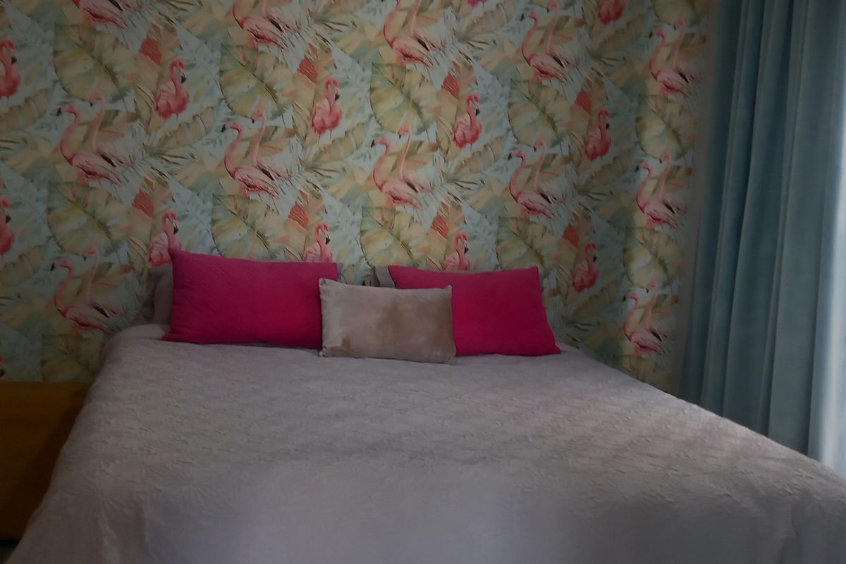 A bedroom featuring a patterned accent wall and built-in storage, offering a functional space with potential for modern updates.