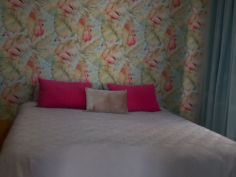 A bedroom featuring a patterned accent wall and built-in storage, offering a functional space with potential for modern updates.