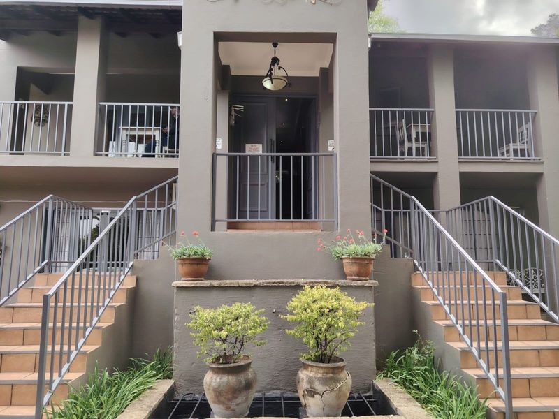 Front elevation of a multi-level property featuring symmetrical staircases, metal railings, and covered balconies leading to a central entrance.