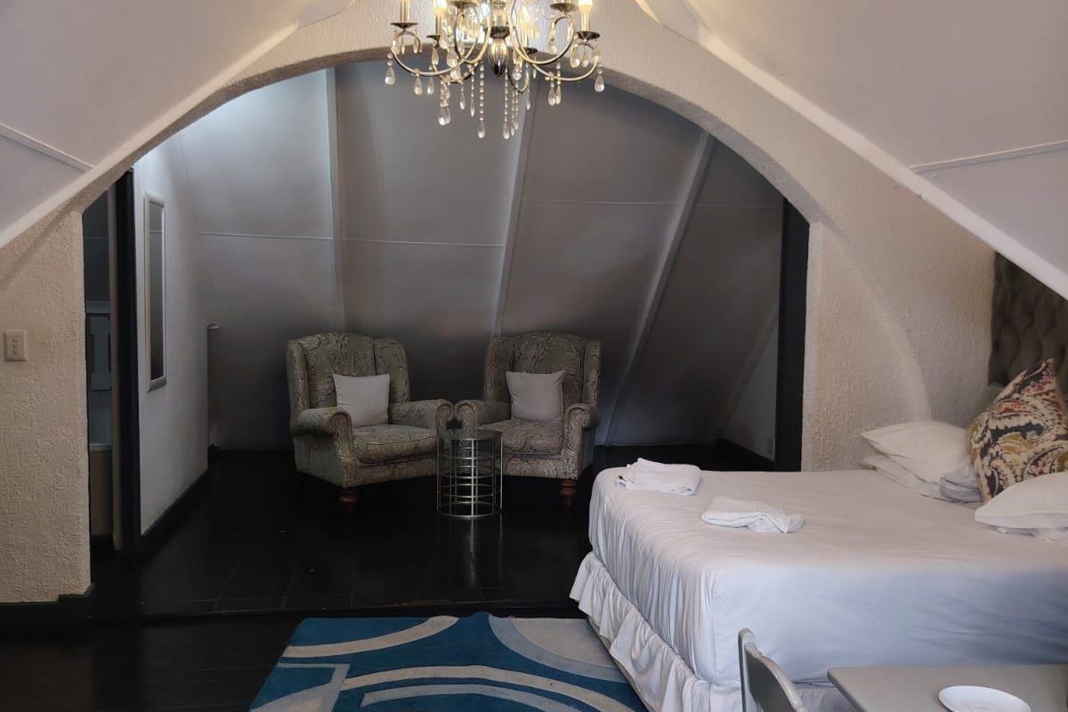Spacious bedroom featuring a unique vaulted ceiling with an arched architectural detail, a central chandelier, and dark timber flooring.