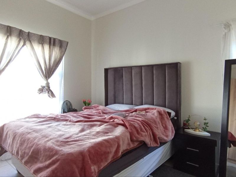 A well-lit bedroom featuring tiled flooring and neutral wall finishes, providing a comfortable and functional living space.