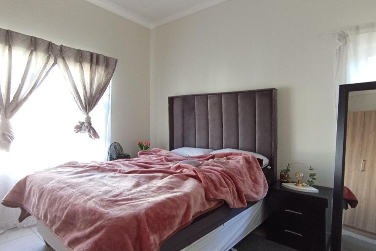 A well-lit bedroom featuring tiled flooring and neutral wall finishes, providing a comfortable and functional living space.