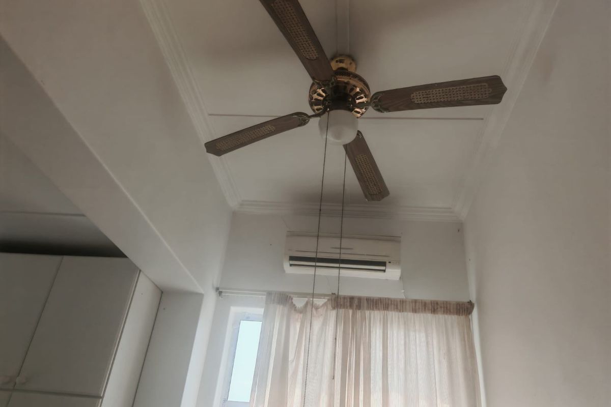 A bedroom interior featuring a ceiling fan, wall-mounted split system air conditioner, and built-in cabinetry.
