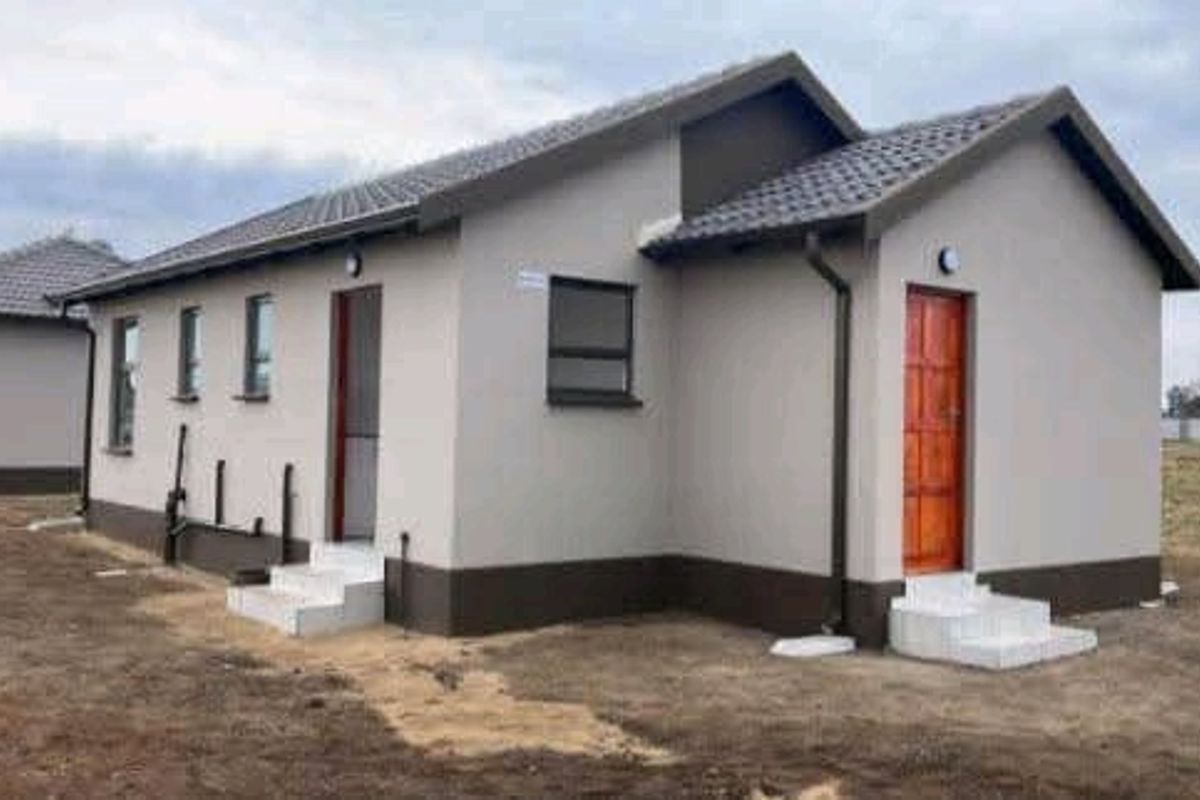 Rear view of a modern townhouse featuring a tiled roof, neutral exterior paint, aluminium window frames, and concrete entry steps.