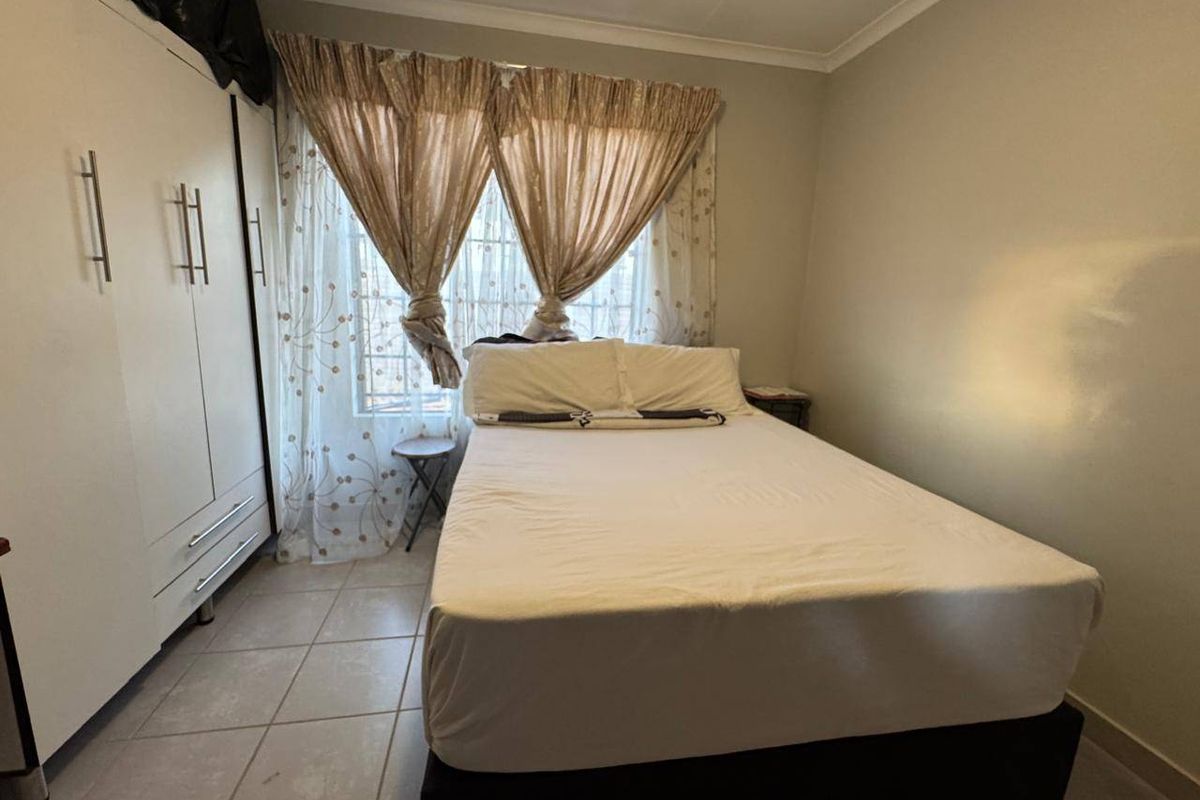 A functional bedroom featuring tiled flooring and a built-in wardrobe, providing practical storage space.