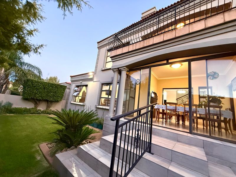 Rear view of the townhouse featuring a tiled patio with wrought iron railings, sliding glass doors, and a well-maintained garden.