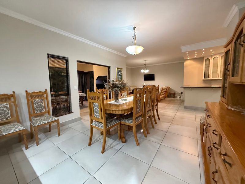 Spacious open-plan dining and living area featuring tiled floors, recessed lighting, and a breakfast bar, offering a functional layout for family living.