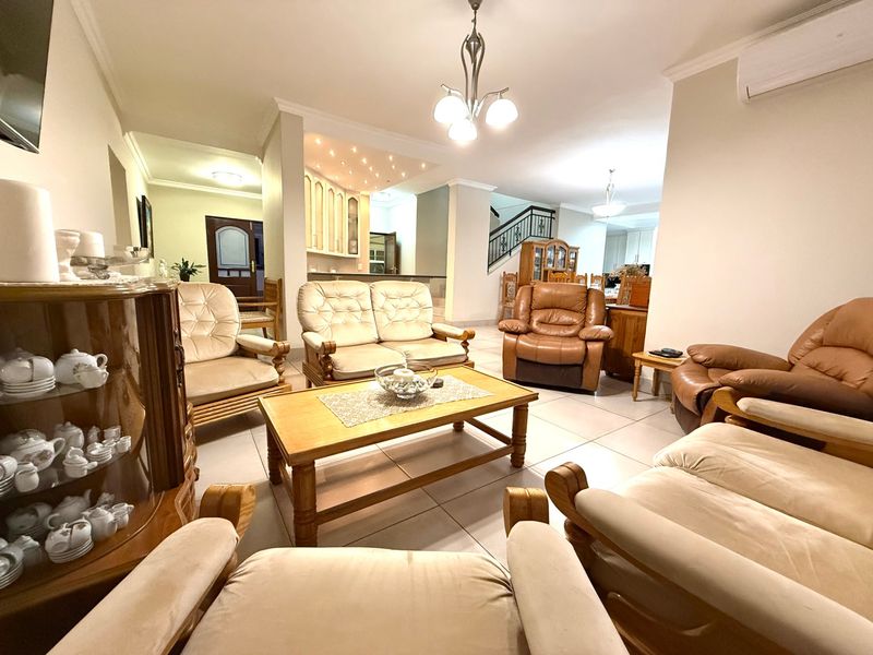 Spacious open-plan living area featuring tiled floors, recessed lighting, and a staircase, seamlessly connecting to the kitchen and dining space.