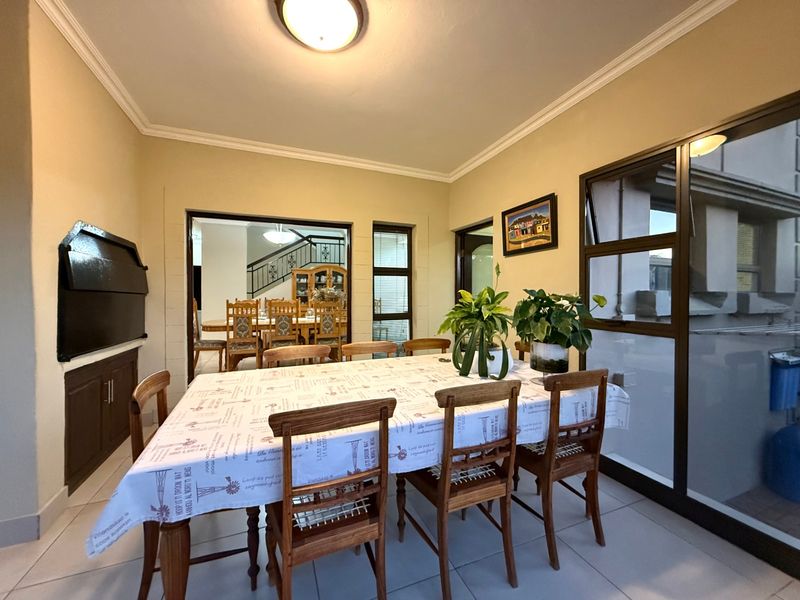 Dining room featuring tiled flooring, a built-in braai, and access to an outdoor area through sliding aluminium doors.