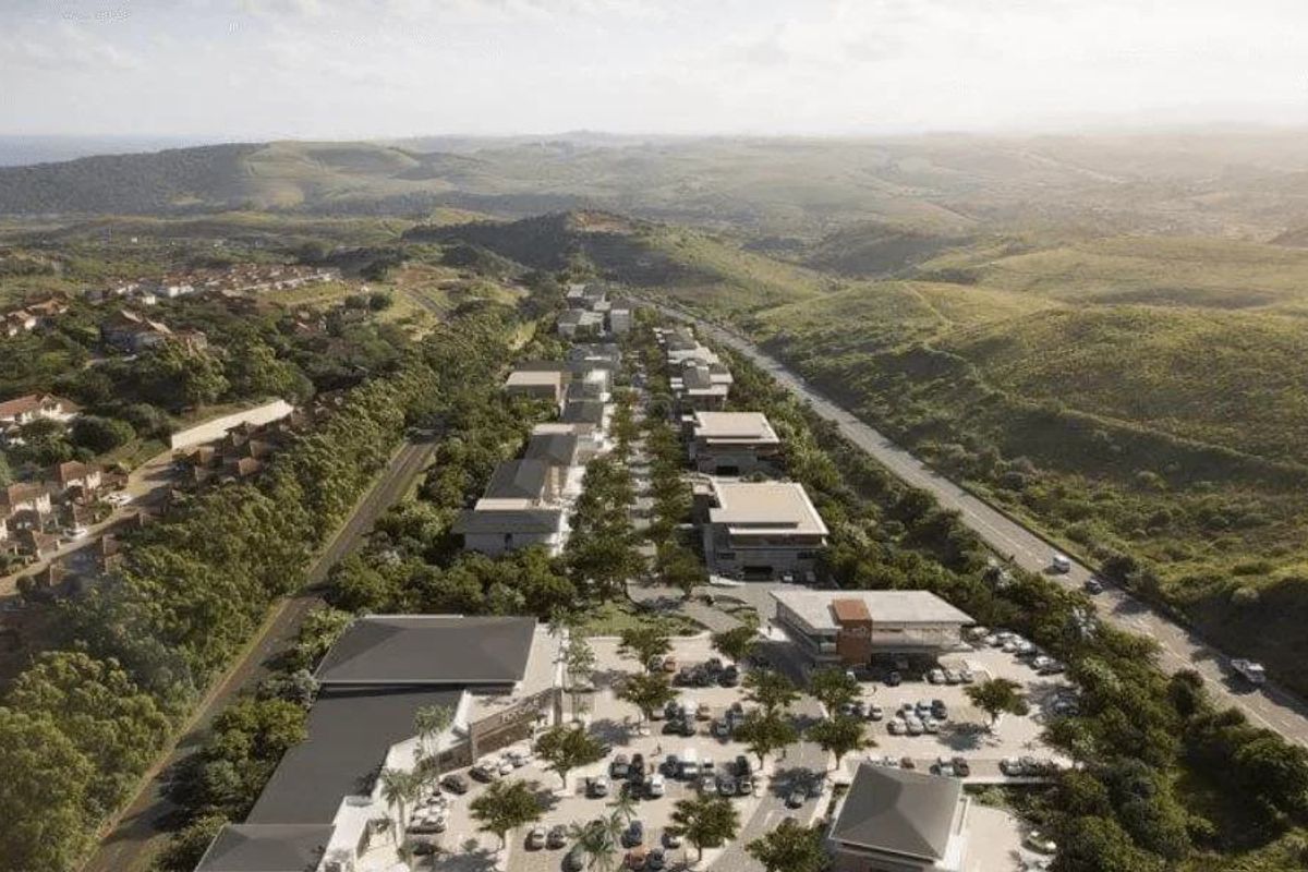 An aerial perspective of a modern residential and commercial development nestled within a scenic, hilly landscape.