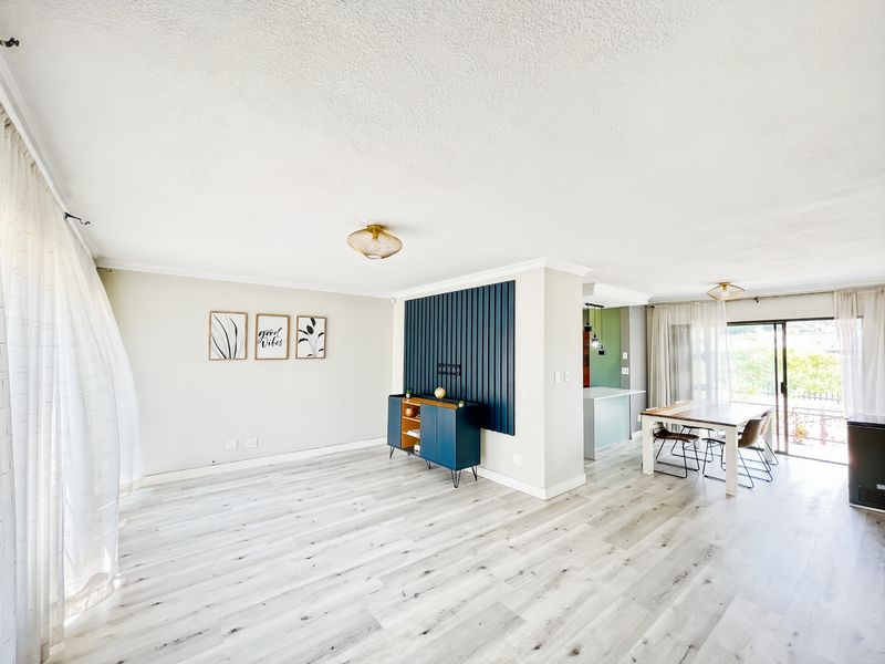 Bright open-plan living and dining area featuring modern laminate flooring, a decorative slat wall feature, and sliding glass doors leading to the exterior.