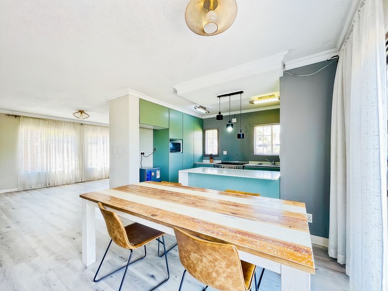Modern open-plan living and dining area featuring a contemporary kitchen with a central island, sleek cabinetry, and integrated appliances.