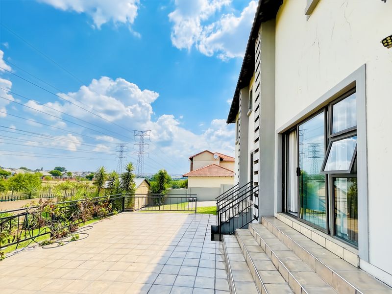 Spacious tiled patio area featuring wrought iron railings, external stairs, and large sliding glass doors providing access to the home's interior.