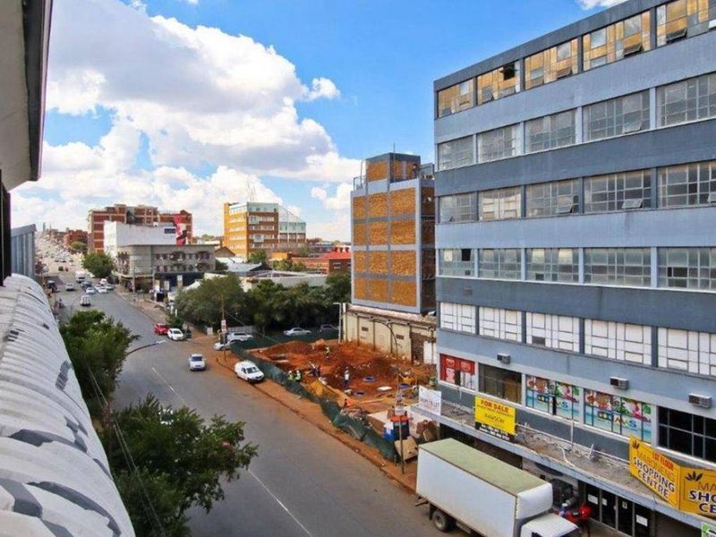 Elevated urban view overlooking a city street, neighboring commercial buildings, and active construction site.