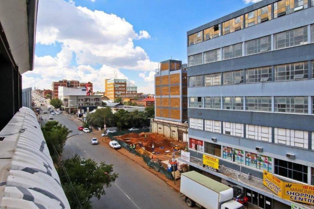 Elevated urban view overlooking a city street, neighboring commercial buildings, and active construction site.