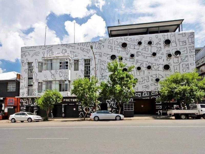 Street-level view of an apartment building featuring a distinctive mural-covered facade and circular window design.