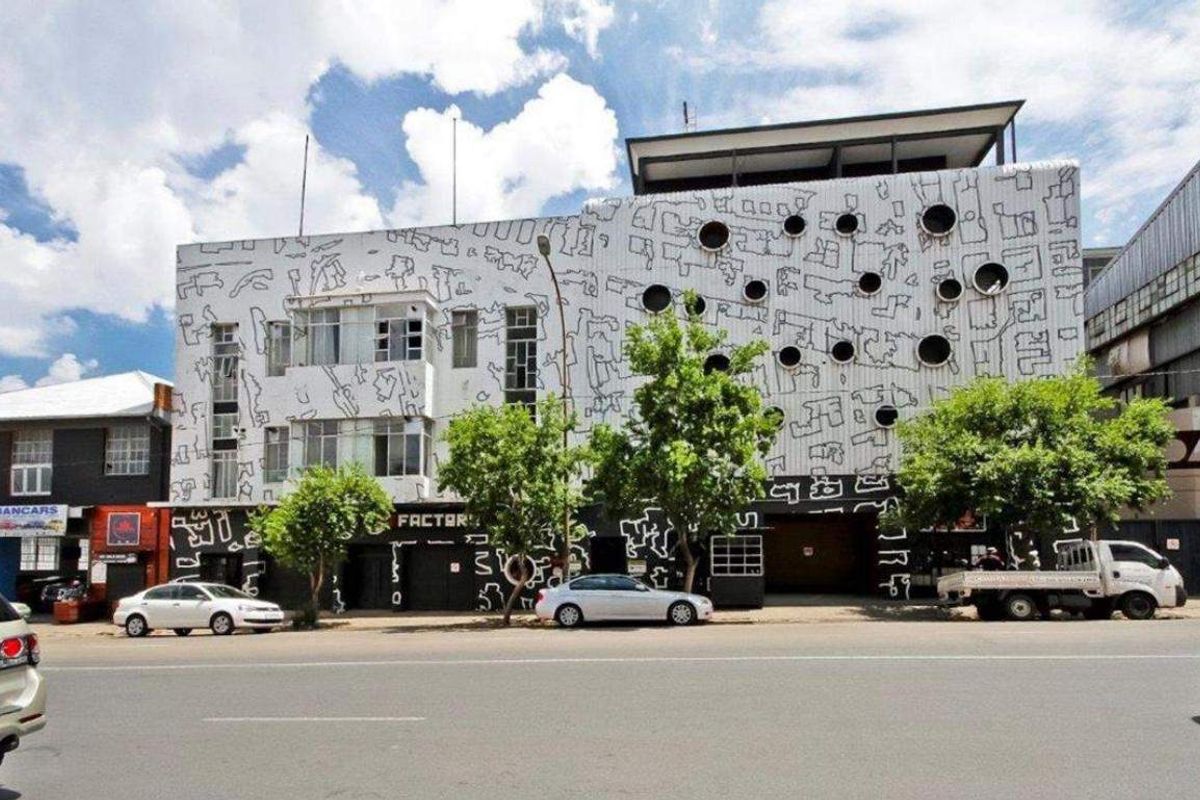 Street-level view of an apartment building featuring a distinctive mural-covered facade and circular window design.