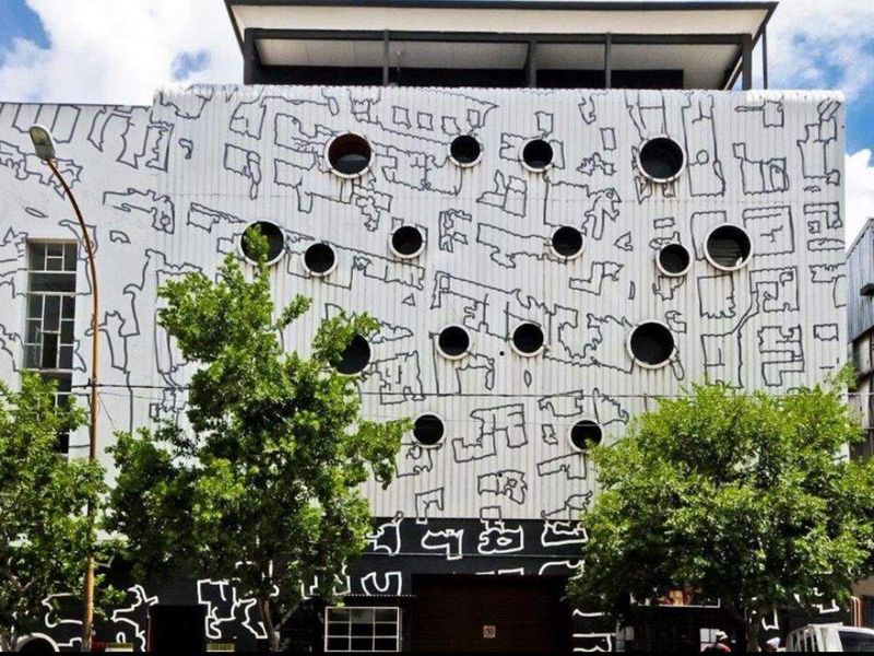 Front elevation of an apartment building featuring a distinctive graphic mural facade and circular window design.