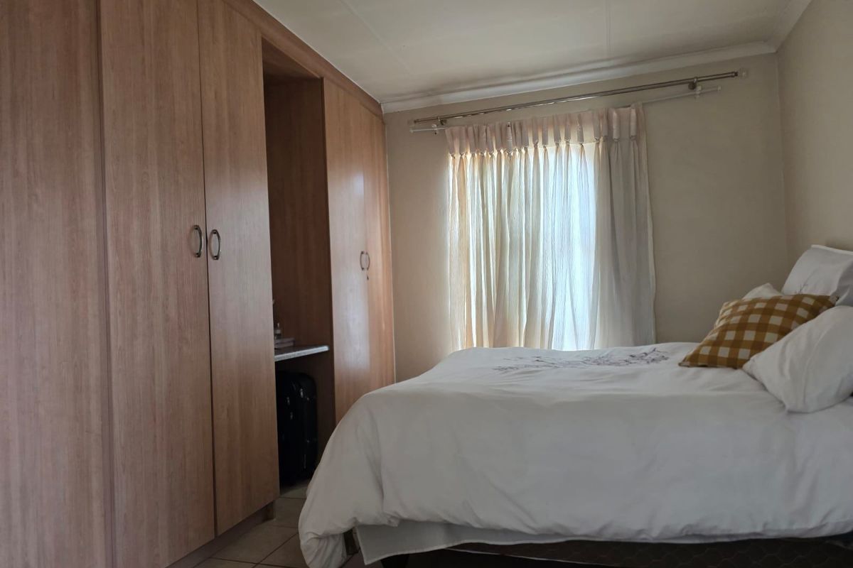 A bedroom featuring light wood-finish built-in cupboards and tiled flooring, providing functional storage space.