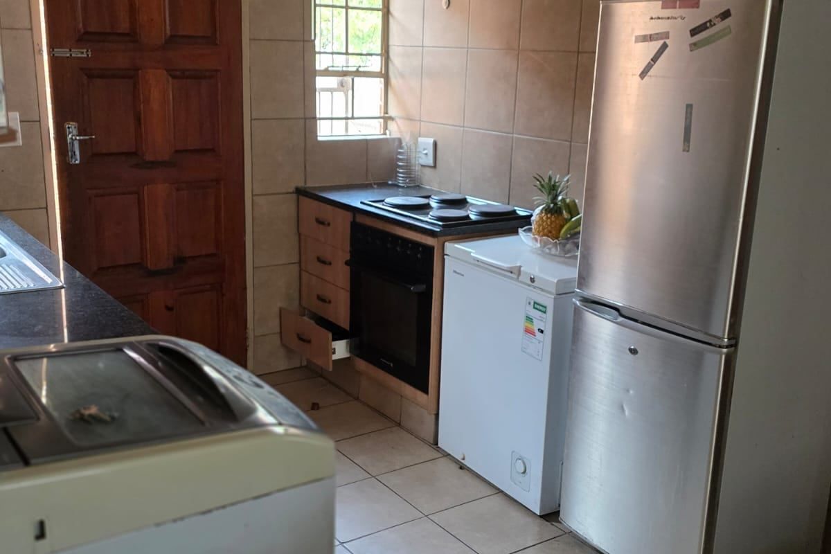 A functional kitchen featuring tiled walls and flooring, built-in oven and hob, and direct access to an exterior door.