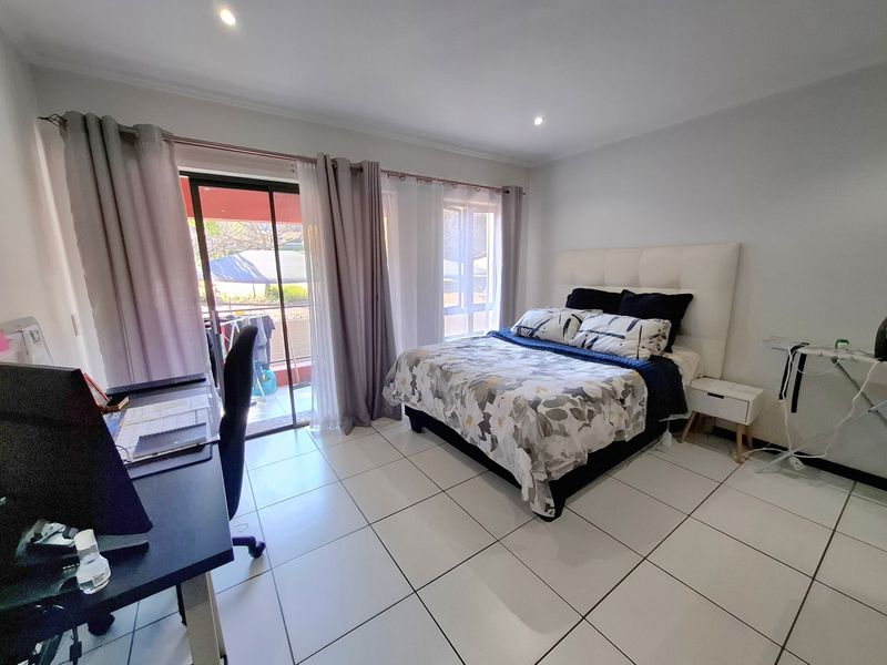 Spacious bedroom featuring tiled flooring, recessed lighting, and a sliding glass door providing direct access to an outdoor balcony area.