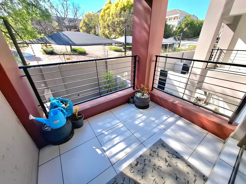 A covered balcony featuring tiled flooring and a modern metal balustrade, offering an open outdoor space.